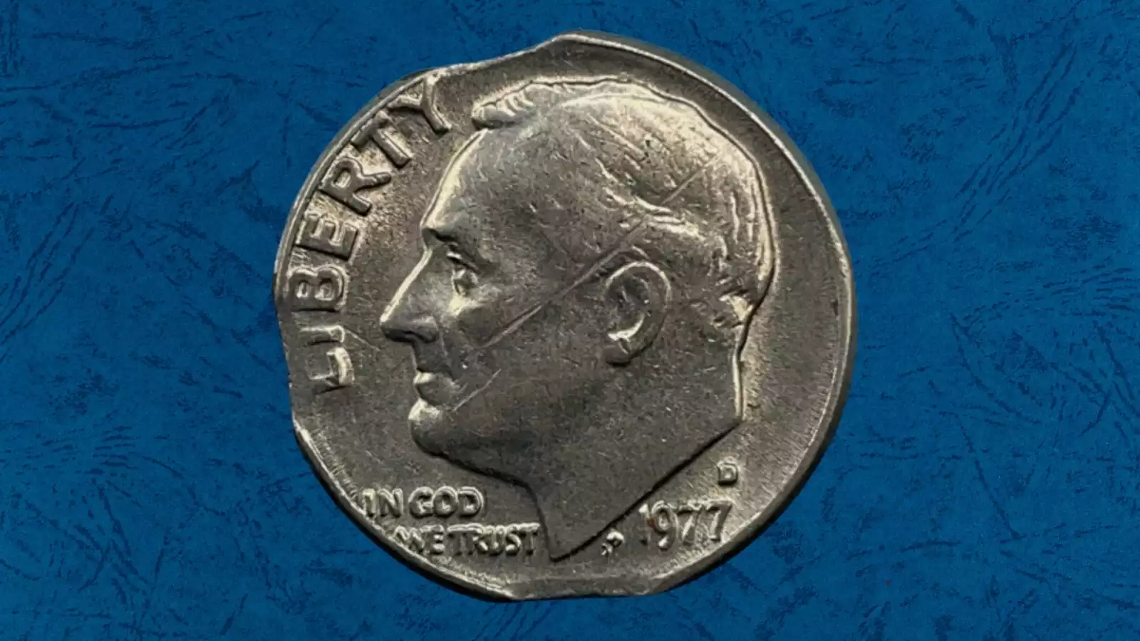 1977 Roosevelt dime clipped planchet error with curved missing section at the edge and Blakesley Effect opposite